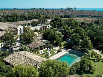 Pool and wellness area, with chapel and main courtyard behind and sea visible in distance